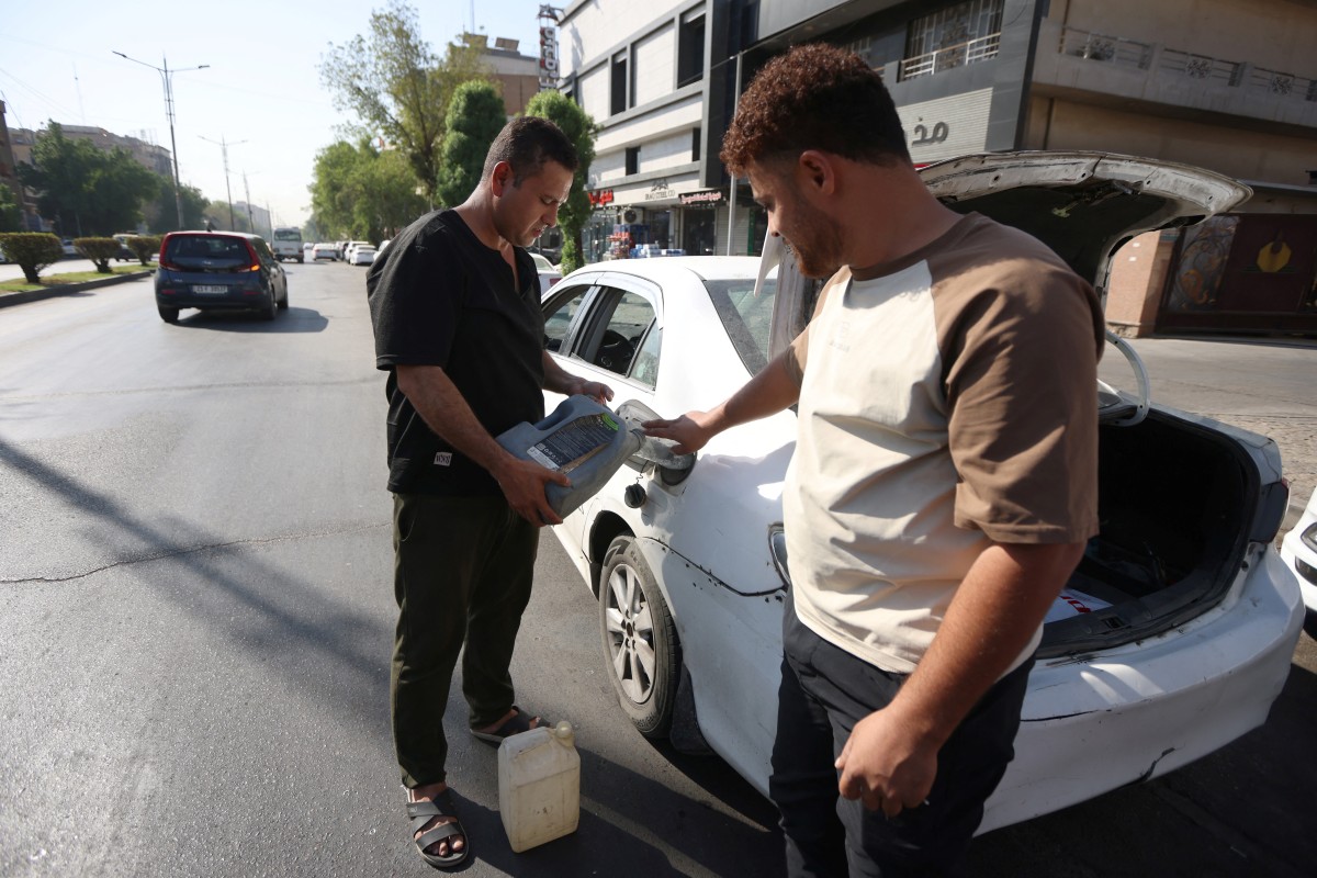 رجل يستخدم عبوة لتعبئة سيارته بالوقود، فيما تتشكّل طوابير أمام محطات الوقود في أنحاء العاصمة العراقية بغداد (أ ف ب),