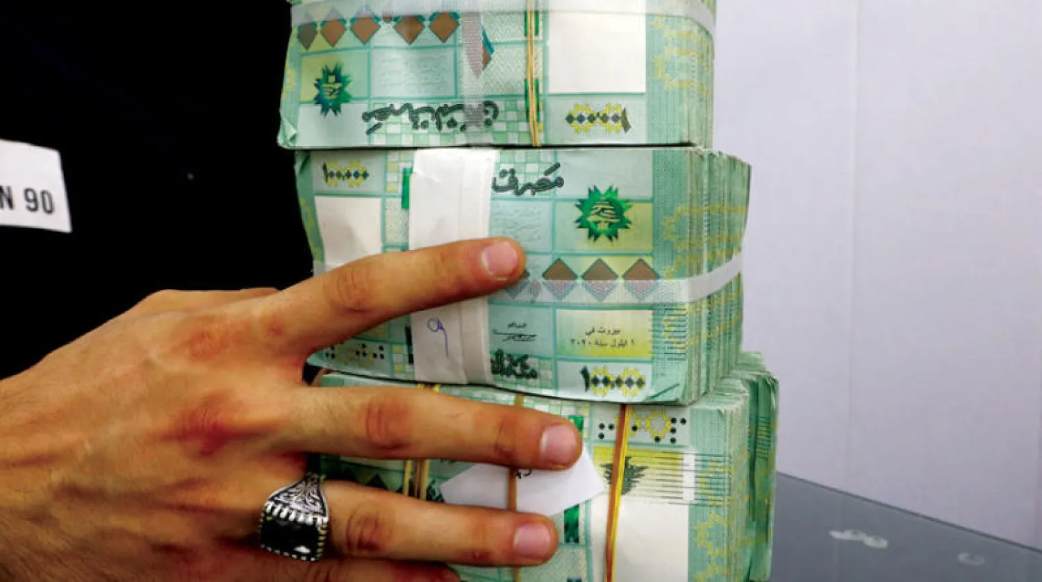  صراف يحمل رزما من العملة اللبنانية في أحد محال الصرافة ببيروت (رويترز)