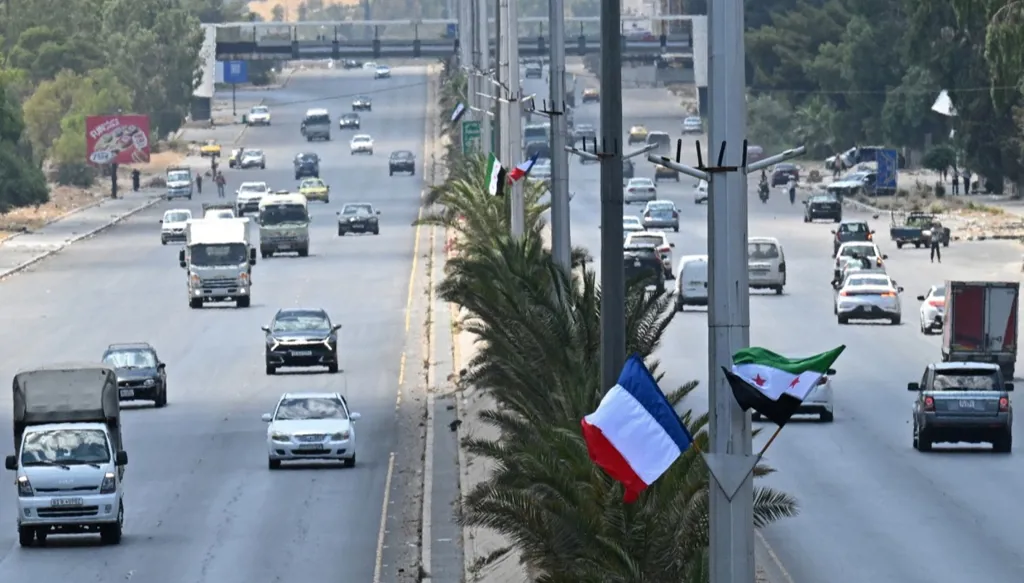 علما سوريا وفرنسا في أحد شوارع دمشق (أ ف ب)