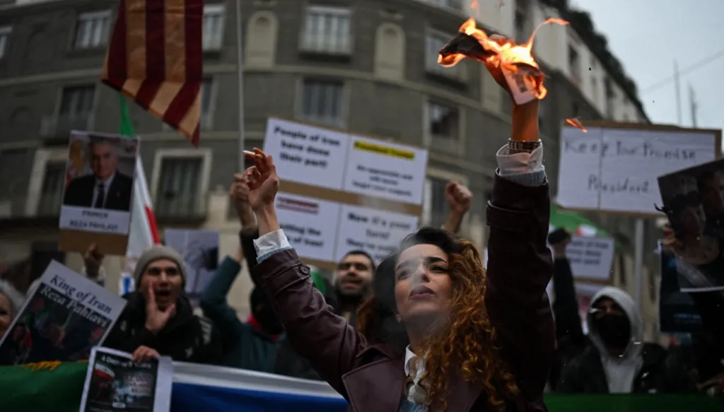 متظاهرة في إيطاليا تحمل ورقة مشتعلة عليها صورة علي خامنئي (أ ف ب)