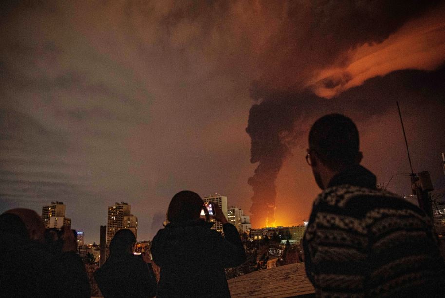سكان يراقبون ويصورون النيران والدخان المتصاعد من منشأة لتخزين النفط تعرضت للقصف في طهران، (أ ب).