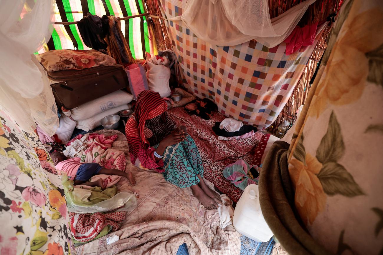 امرأة تبلغ من العمر 24 عاماً، تقول إنها حملت بعد أن تعرضت لاعتداء من قبل مسلحَين في غرب دارفور، تقف إلى جانب طفلها الصغير داخل مأوى مؤقت في أدري، تشاد، بتاريخ 21 تموز/يوليو 2023 (رويترز).