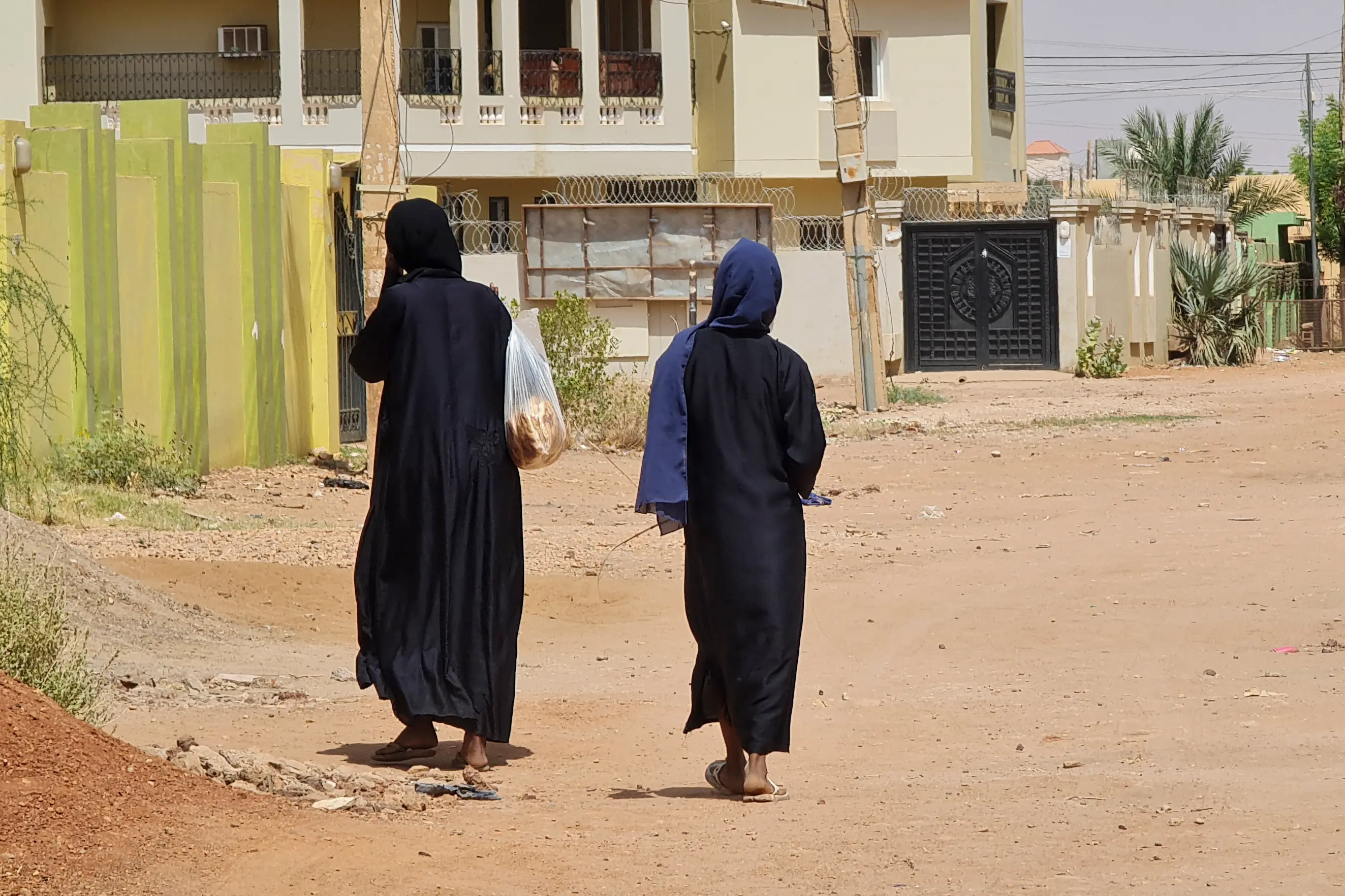 امرأتان تسيران في شارع خالٍ من المارة في حي جبرة في الخرطوم، في 28 مايو/أيار 2023(وكالة فرانس برس)