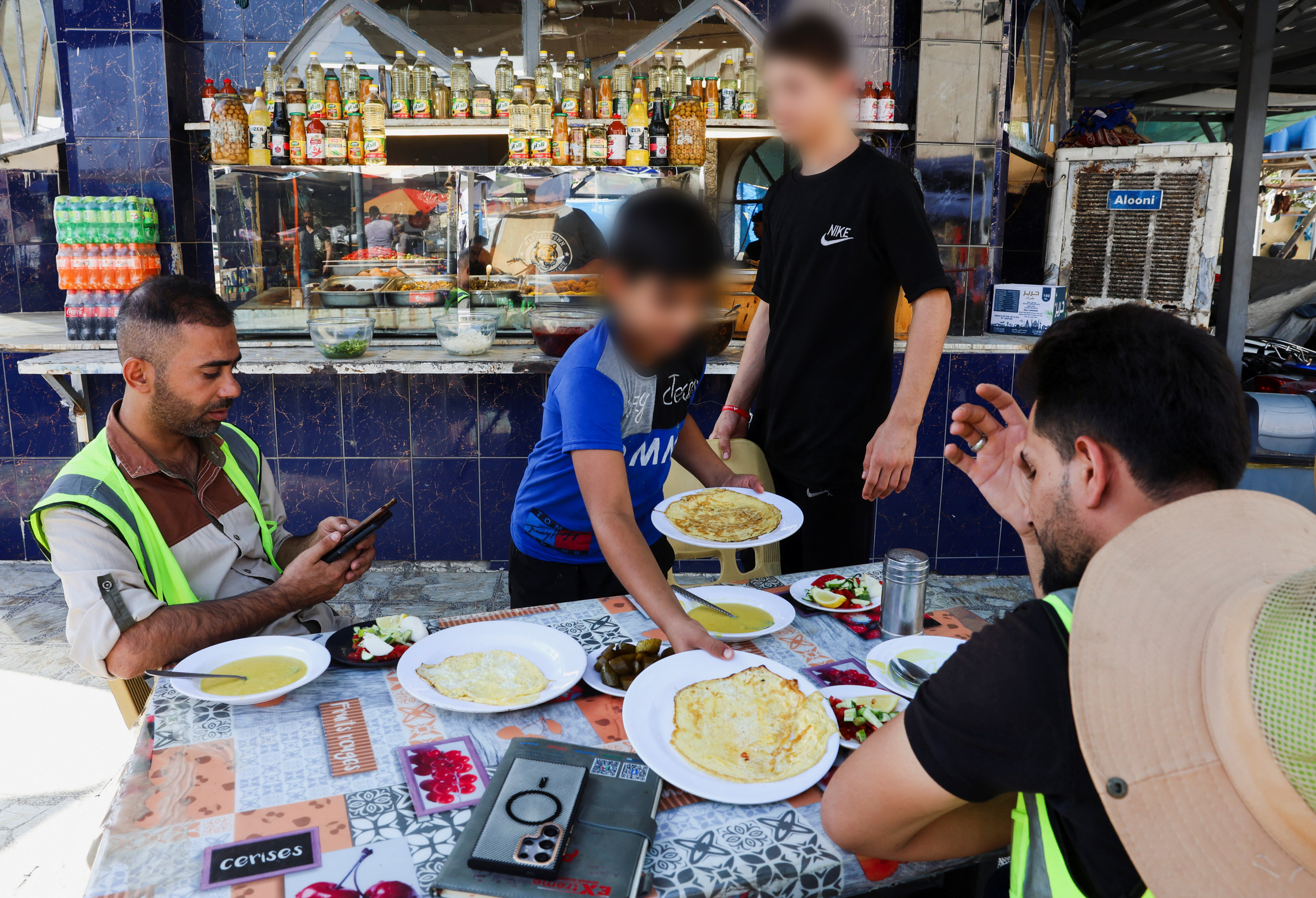 صبي يقدم الطعام لزبائن في مطعم ببغداد (9 ايلول 2025، رويترز).