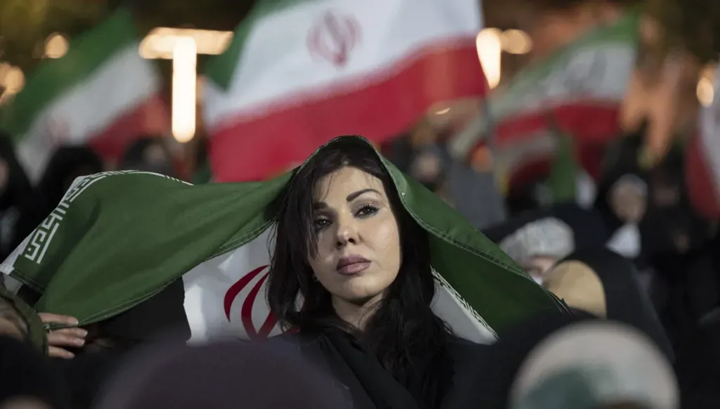 سيدة ترفع علم إيران خلال مراسم زفاف جماعي نظمها الحرس الثوري في شمال طهران. (رويترز)