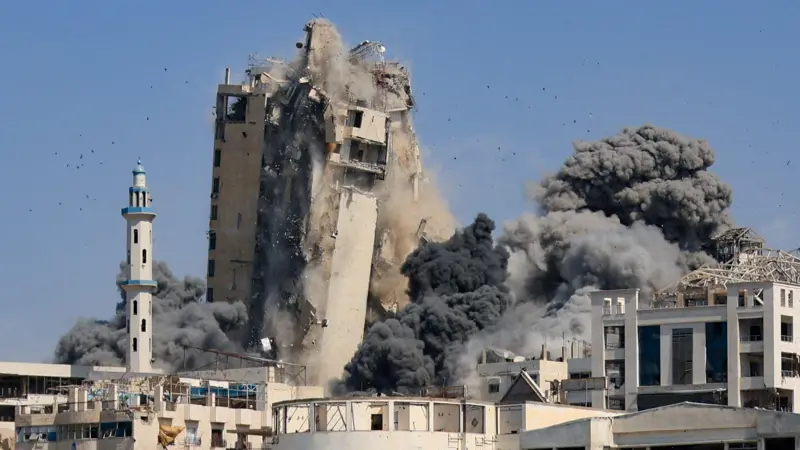 دخان يتصاعد من برج سكني بعد انهياره إثر غارات جوية إسرائيلية في مدينة غزة (أرشيفية)