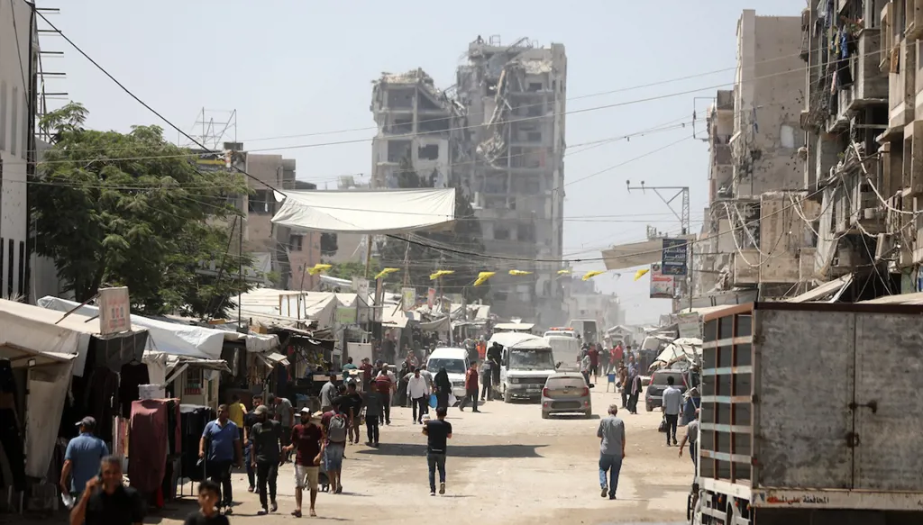 فلسطينيون يتنقلون بين خيام ومبانٍ متضررة في أحد شوارع قطاع غزة، وسط تدهور الأوضاع المعيشية والخدمات. (أ ب أ)