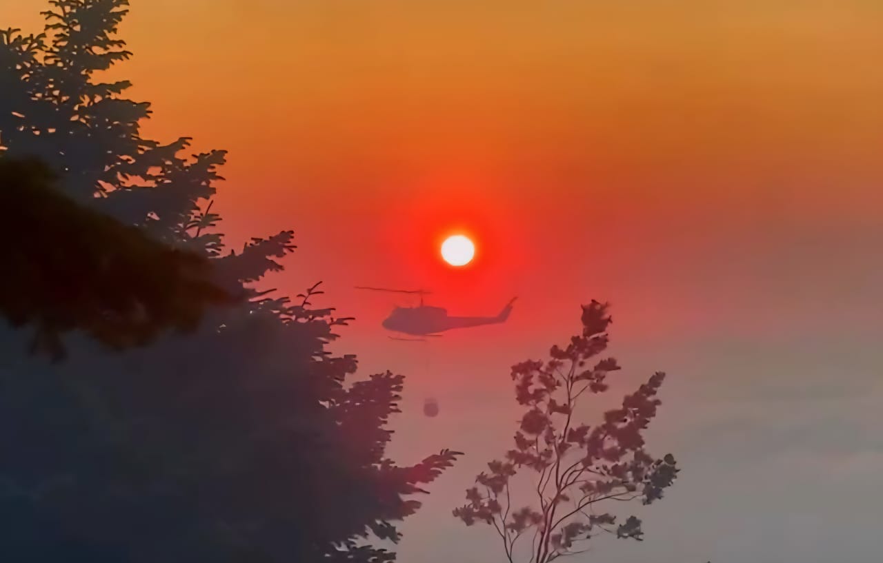 دخان الحريق يحجب الشمس فيما تكافح طوافة عسكرية النار. (ميشال حلاق)