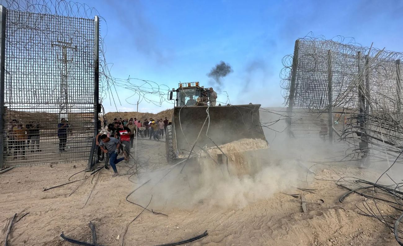 فلسطينيون يقتحمون الجانب الإسرائيلي من السياج الحدودي مع غزة بعد تسلل مسلحين إلى مناطق جنوب إسرائيل خلال هجوم 7 أكتوبر، (رويترز).