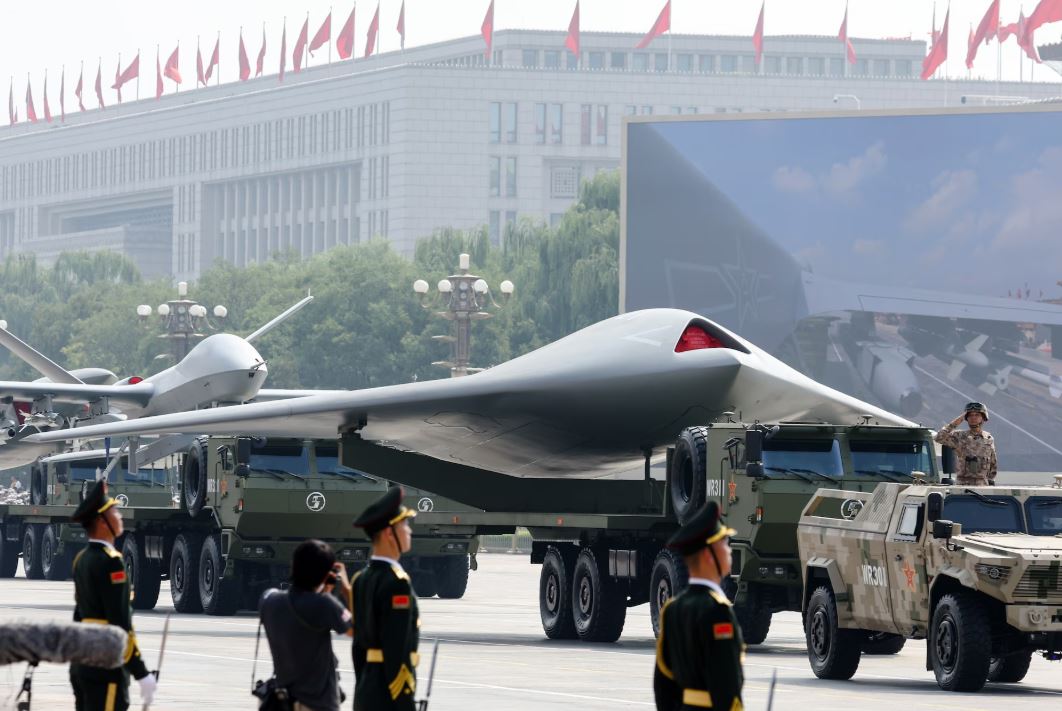 أعضاء من الجيش الصيني يقفون أثناء عرض طائرات بدون طيار خلال العرض العسكري (وكالات)