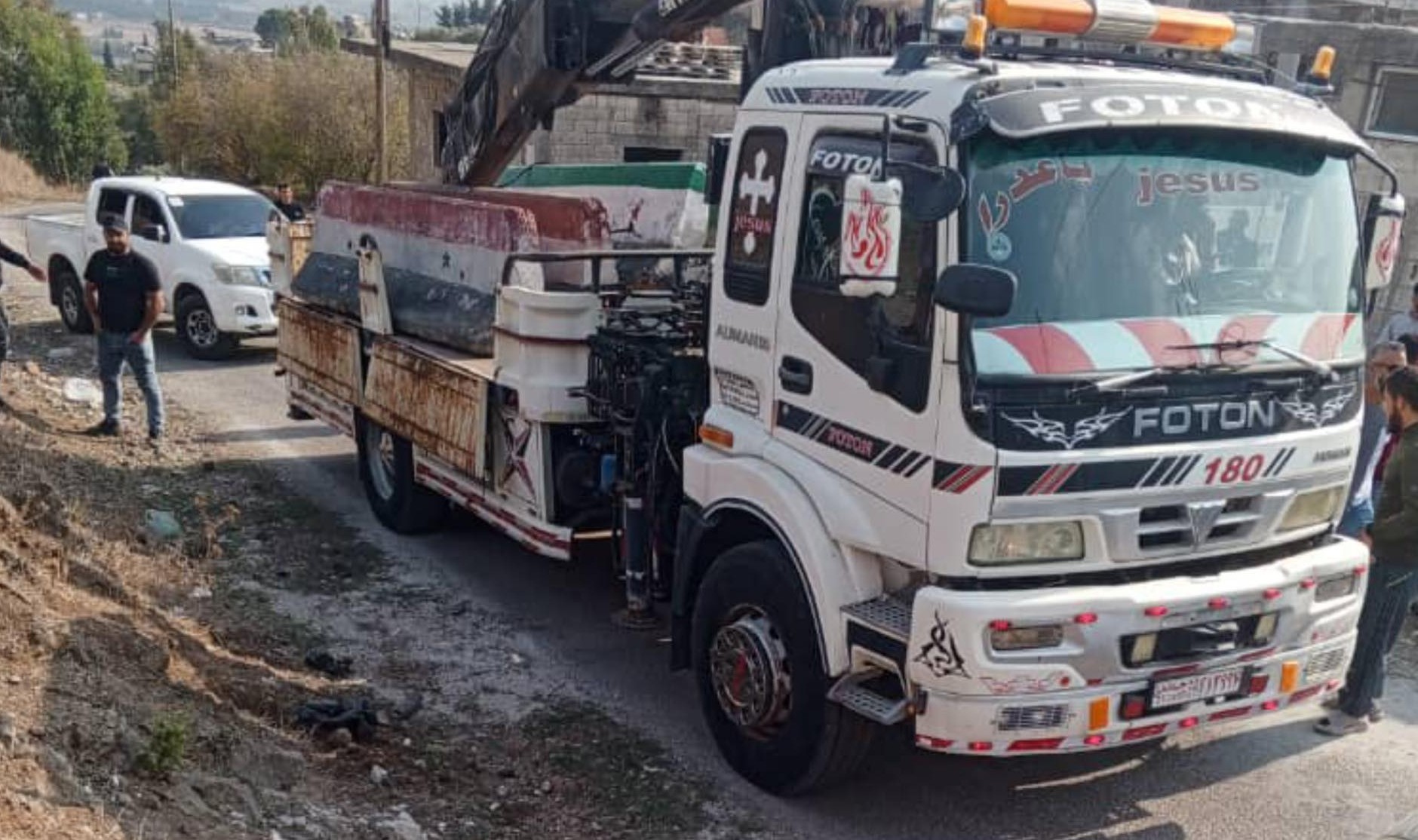 شاحنة تحمل كتلة خرسانية عليها علم سوريا القديم استُخدمت لقطع الطريق. (وسائل تواصل اجتماعي)