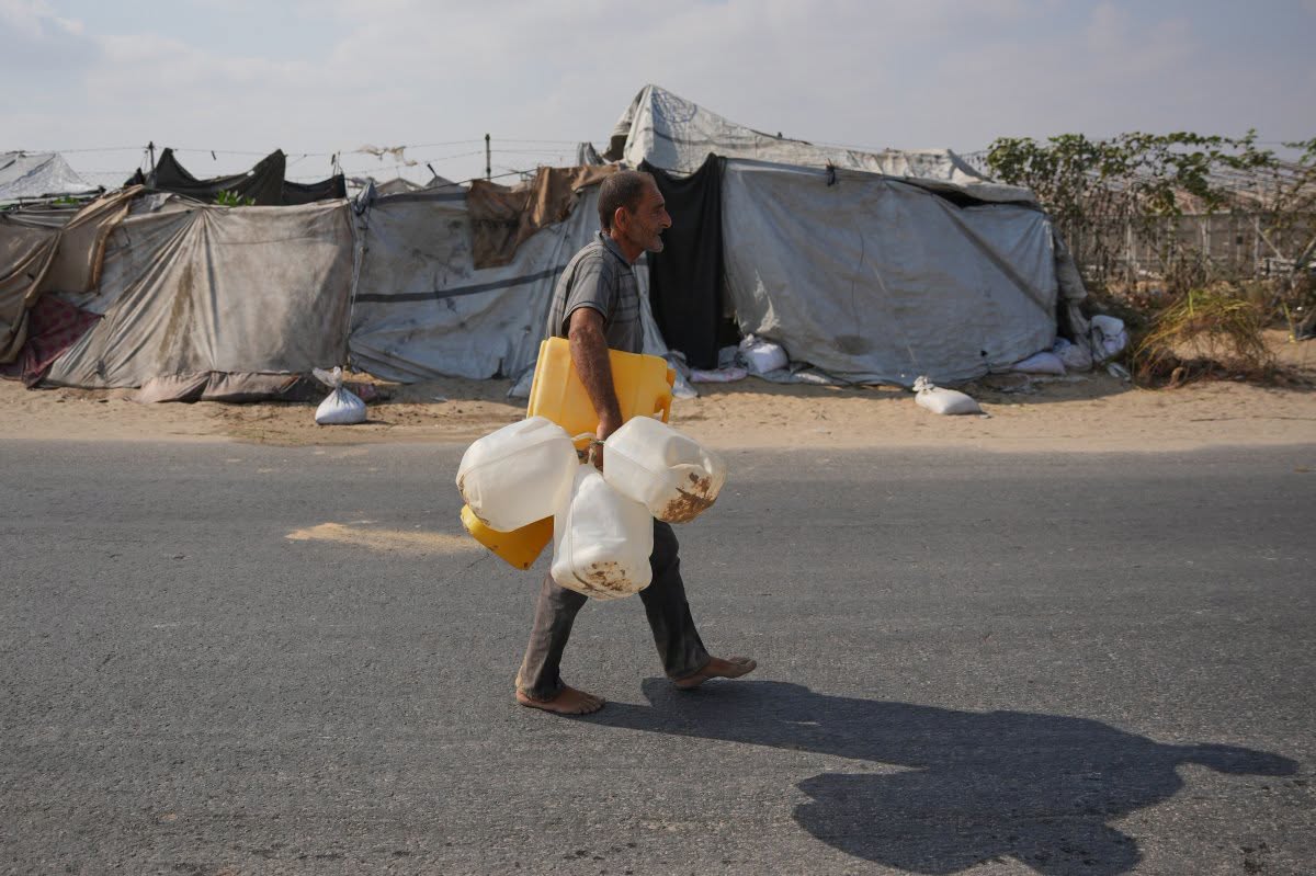 نازح فلسطيني يحمل عبوات فارغة في طريقه للتزوّد بالمياه العذبة في دير البلح وسط قطاع غزة في 14 آب/أغسطس 2026. (أ ب)