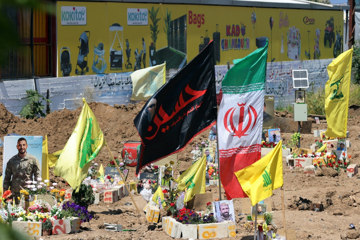 أعلام حزب الله وإيران فوق قبور ضحايا غارات إسرائيلية في مقبرة موقتة في مدينة صور في 30 نيسان/أبريل 2026 (أ ف ب)