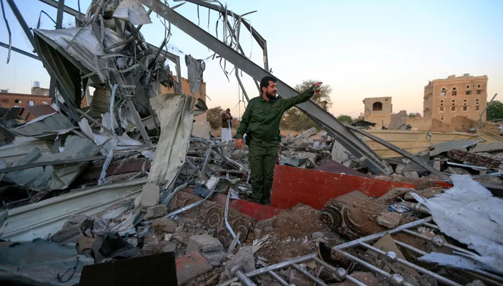 مقاتل حوثي يتفقد الأضرار في منطقة تعرضت لغارة جوية في صنعاء (أ ف ب)