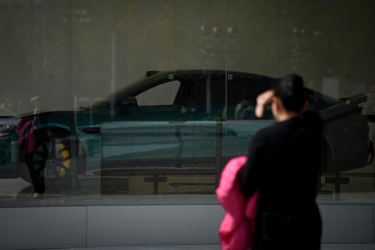 امرأة صينية تنظر الى سيارة كهربائية معروضة في معرض في بكين (ا ف ب)