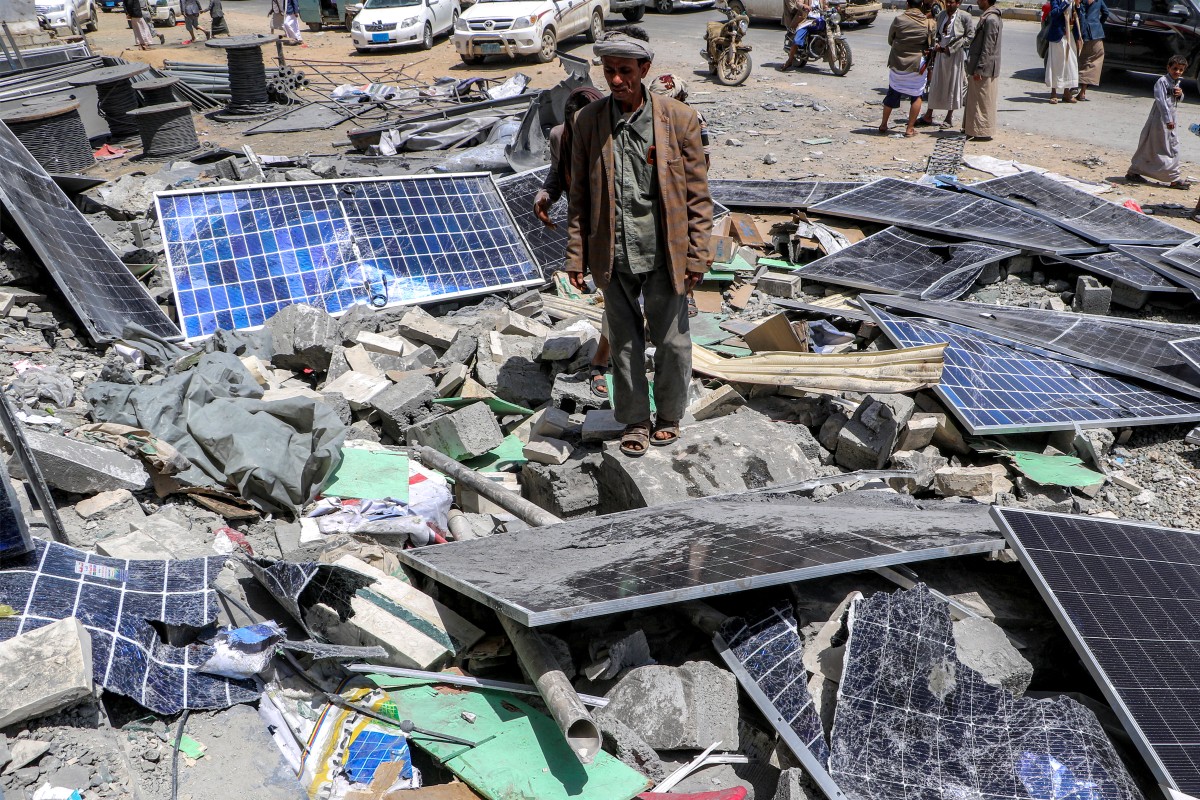 رجل يقف بجانب ألواح شمسية مدمرة في موقع مبنى قيل إنه تعرض لغارة جوية أميركية في محافظة صعدة شمال اليمن (أ ف ب)