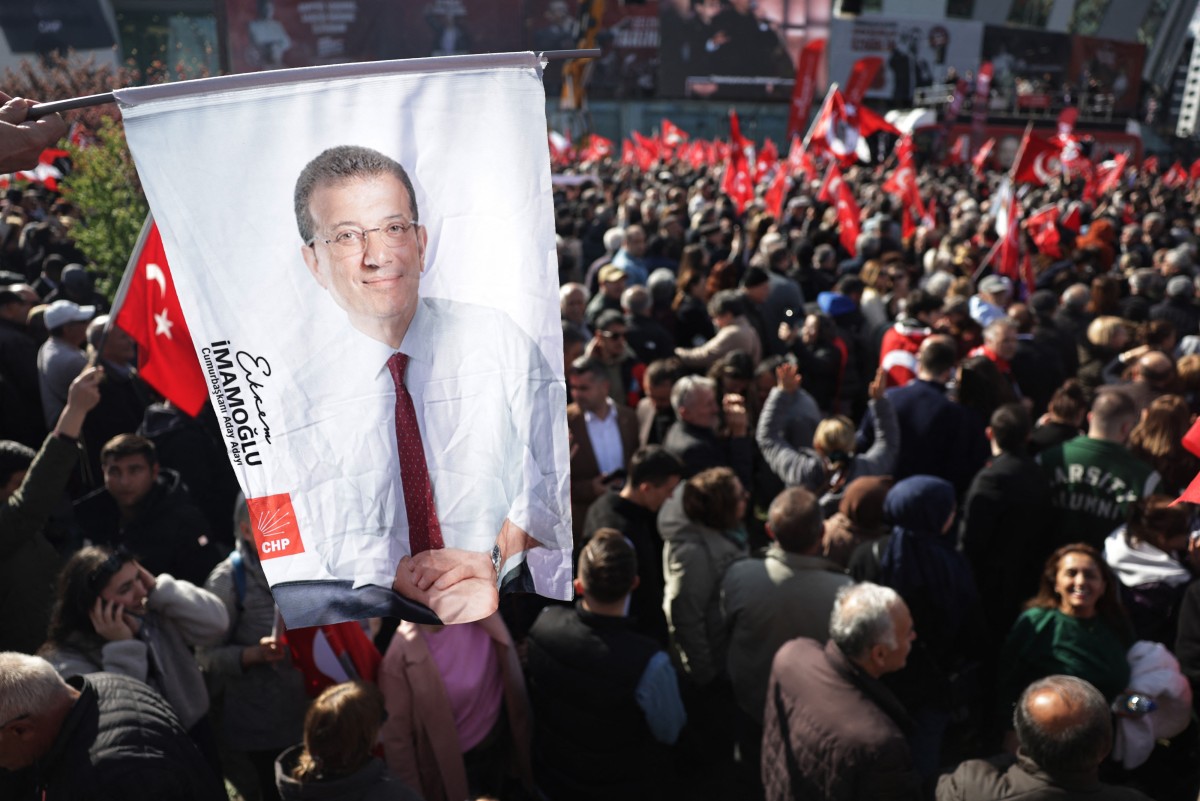 أحد المؤيدين يحمل صورة لرئيس بلدية إسطنبول المسجون أكرم إمام أوغلو (أ ف ب)