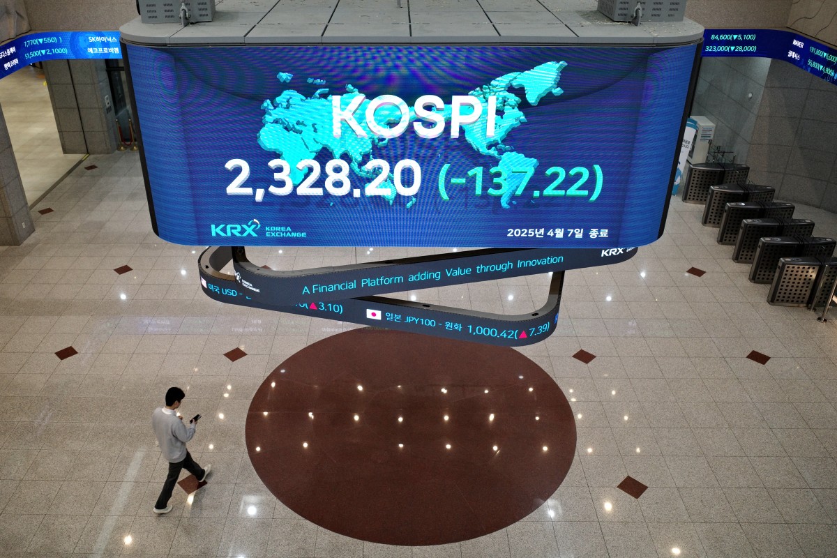 رجل يمشي تحت شاشة تعرض مؤشر كوسبي القياسي. ( أ ف ب)