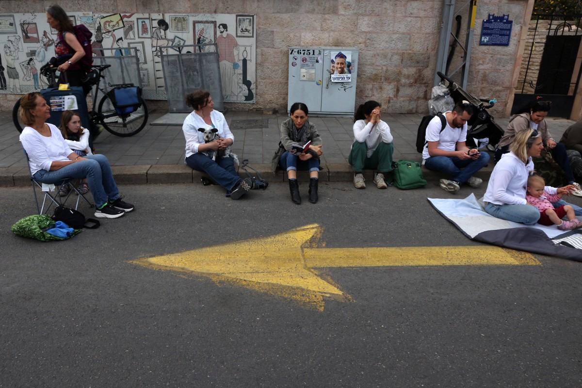 متظاهرون يجلسون على الطريق خارج مقر إقامة رئيس الوزراء الإسرائيلي في القدس (أ ف ب)