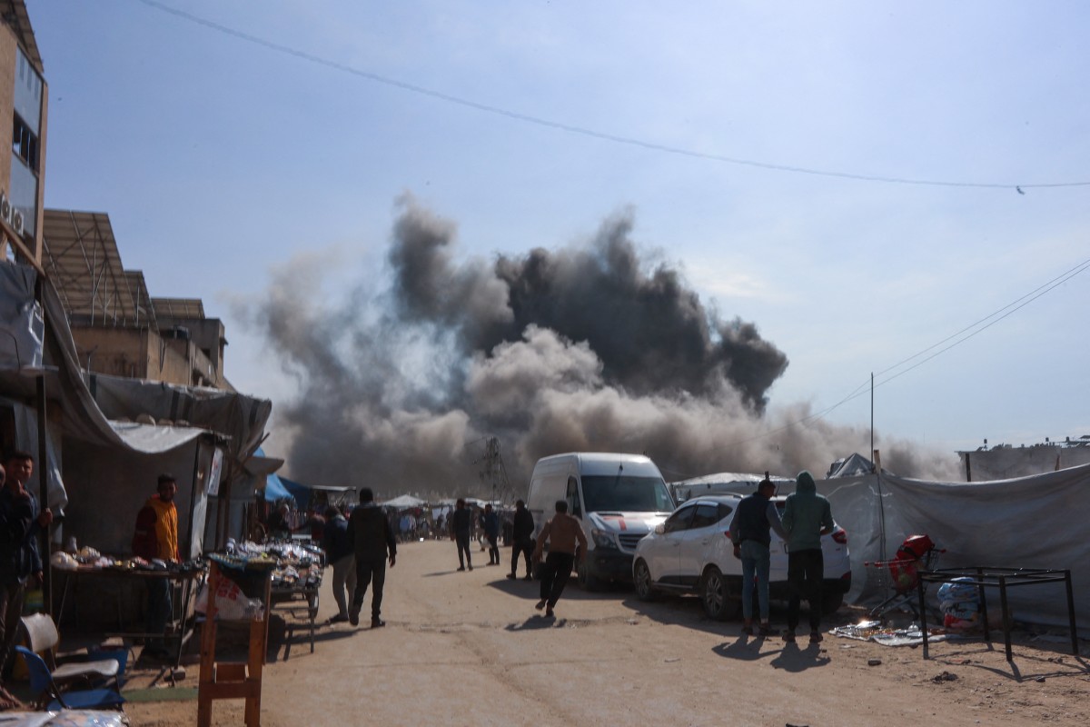 فلسطينيون ينظرون بينما يتصاعد الدخان من غارة إسرائيلية على ورشة حدادة في حي الزيتون في مدينة غزة في 13 أبريل/نيسان 2025 (أ ف ب).