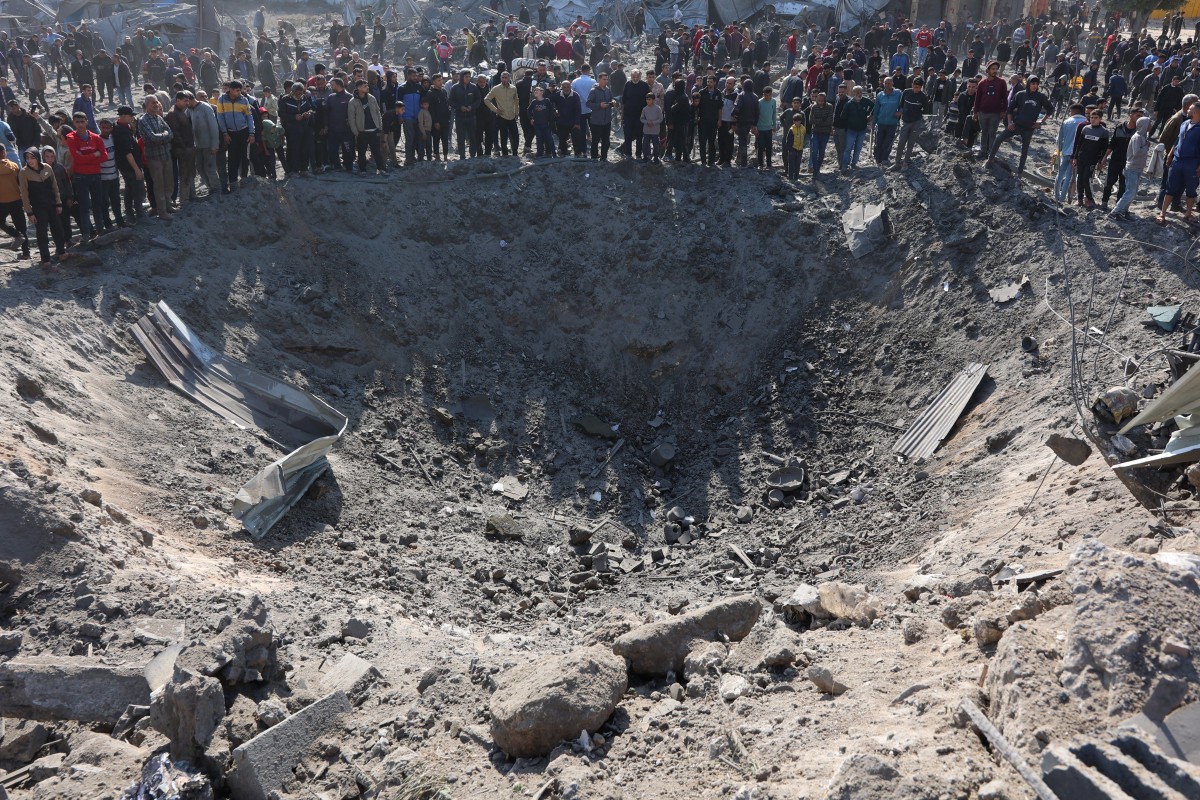 فلسطينيون يتجمعون حول حفرة كبيرة بعد غارة إسرائيلية على ورشة حدادة في حي الزيتون في مدينة غزة (أ ف ب). 