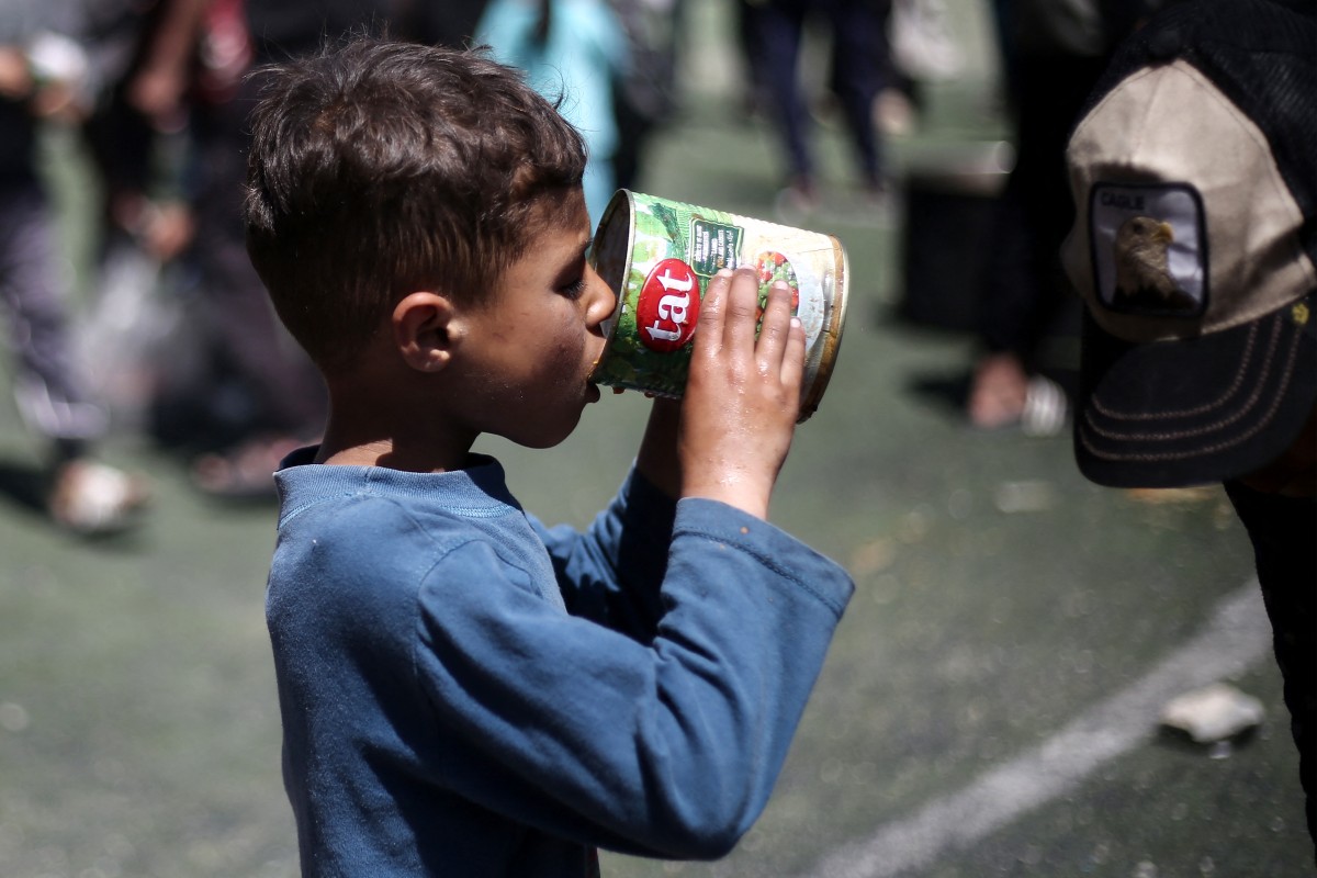 طفل فلسطيني يتناول حصته الغذائية في نقطة توزيع طعام بمخيم النصيرات وسط غزة. (ا ف ب)