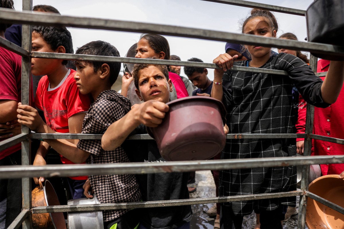 أشخاص يصطفون في طوابير وهم يحملون الأواني لتلقي وجبات الطعام الخيرية من مطبخ في بيت لاهيا