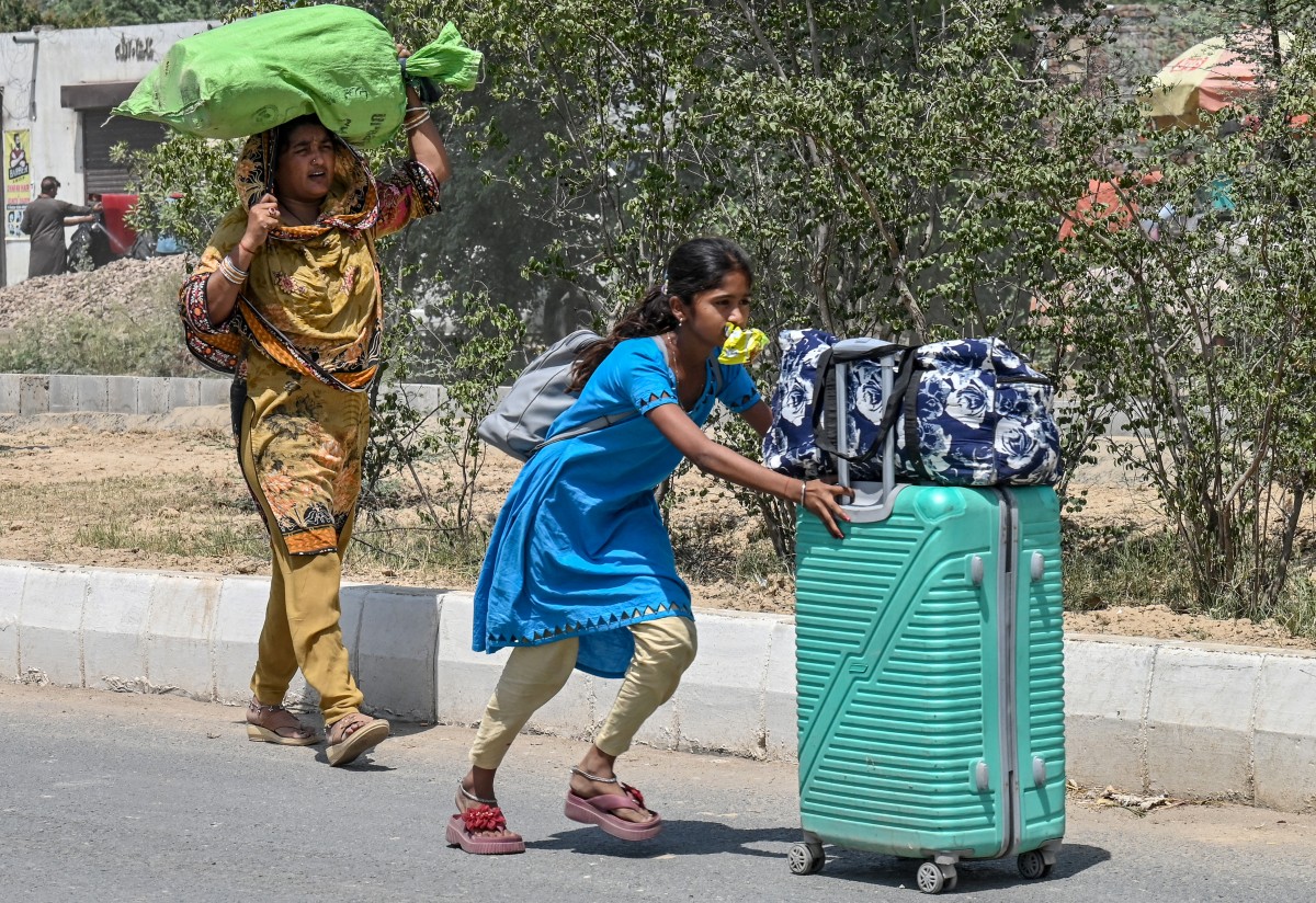 عائلة هندية تحمل أمتعتها أثناء عودتها من باكستان. (أ ف ب)