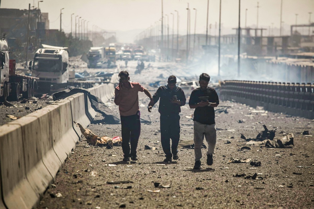 ناس يسيرون على طول شارع مدمر عقب الانفجار في ميناء الشهيد رجائي (ا ف ب)