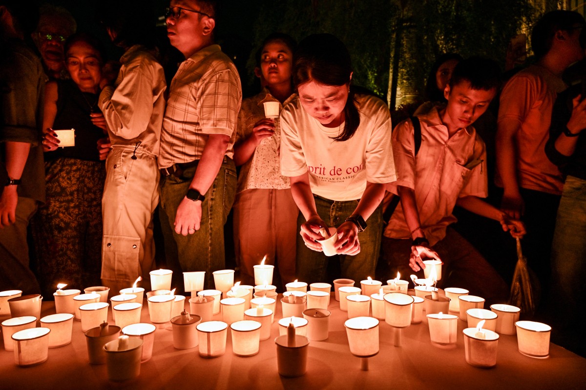 مؤمنون كاثوليك يضيئون الشموع لتوديع البابا الراحل فرانسيس في كاتدرائية سورابايا (أ ف ب).