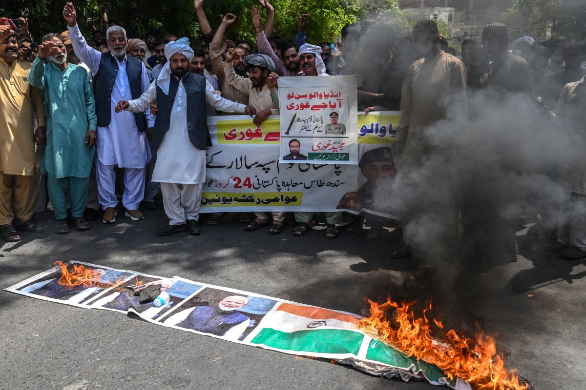 أعضاء اتحاد عوامي للريكشو يحرقون لافتة عليها صور العلم الوطني الهندي ورئيس الوزراء ناريندرا مودي خلال احتجاج مناهض للهند في لاهور  (أ ف ب)