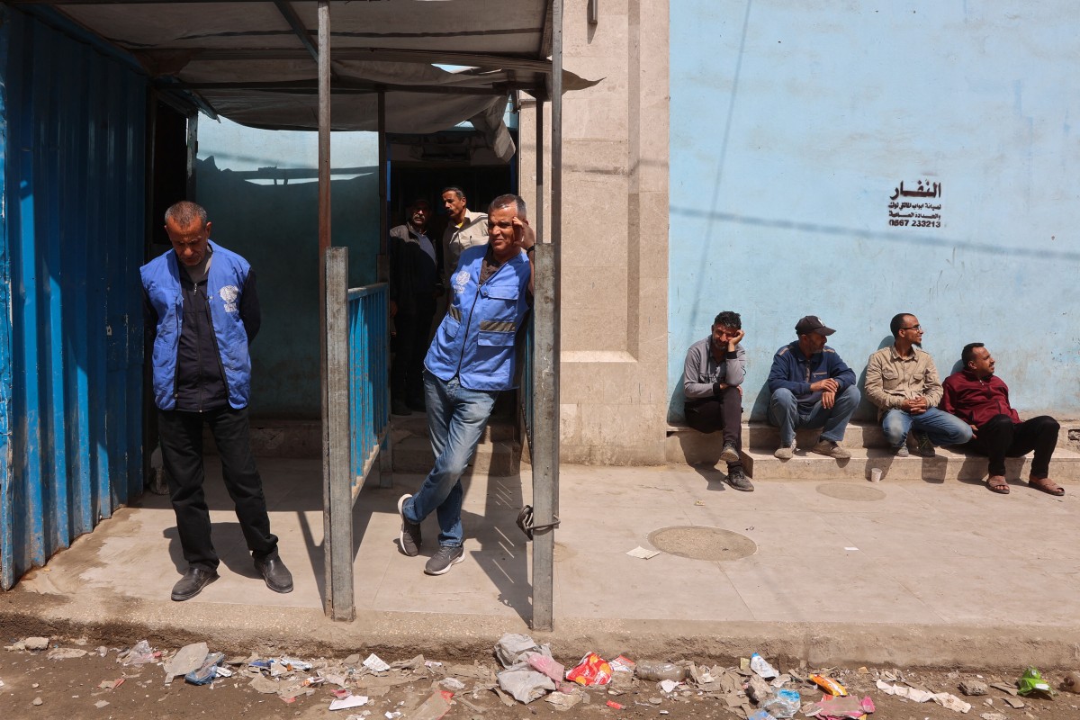 موظفون يقفون عند مدخل مستودع توزيع مساعدات الأونروا المغلق في شارع الجلاء بمدينة غزة (أ ف ب).