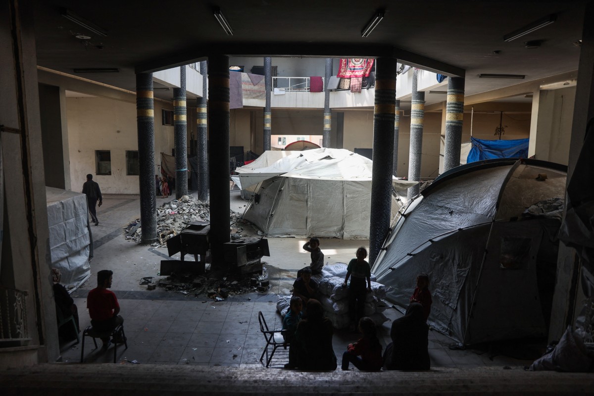 فلسطينيون نازحون يجلسون بجانب خيام منصوبة داخل مبنى في حرم الجامعة الإسلامية المتضرر في غزة (أ ف ب).