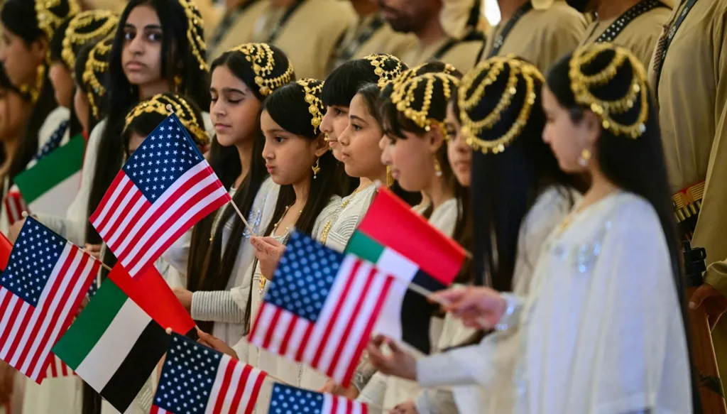 فتيات إمارتيّات يُرحبنَ بـ ترامب على أرض مطار أبوظبي الرئاسي وسط رفع العلمَين الإماراتي والأميركي (أ ف ب)