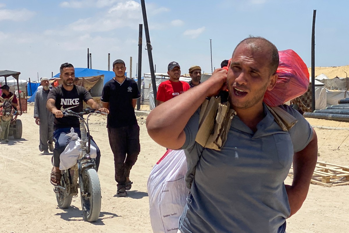 نازحون فلسطينيون يحملون طرودًا أثناء عودتهم من مركز توزيع مساعدات في خان يونس (أ ف ب).