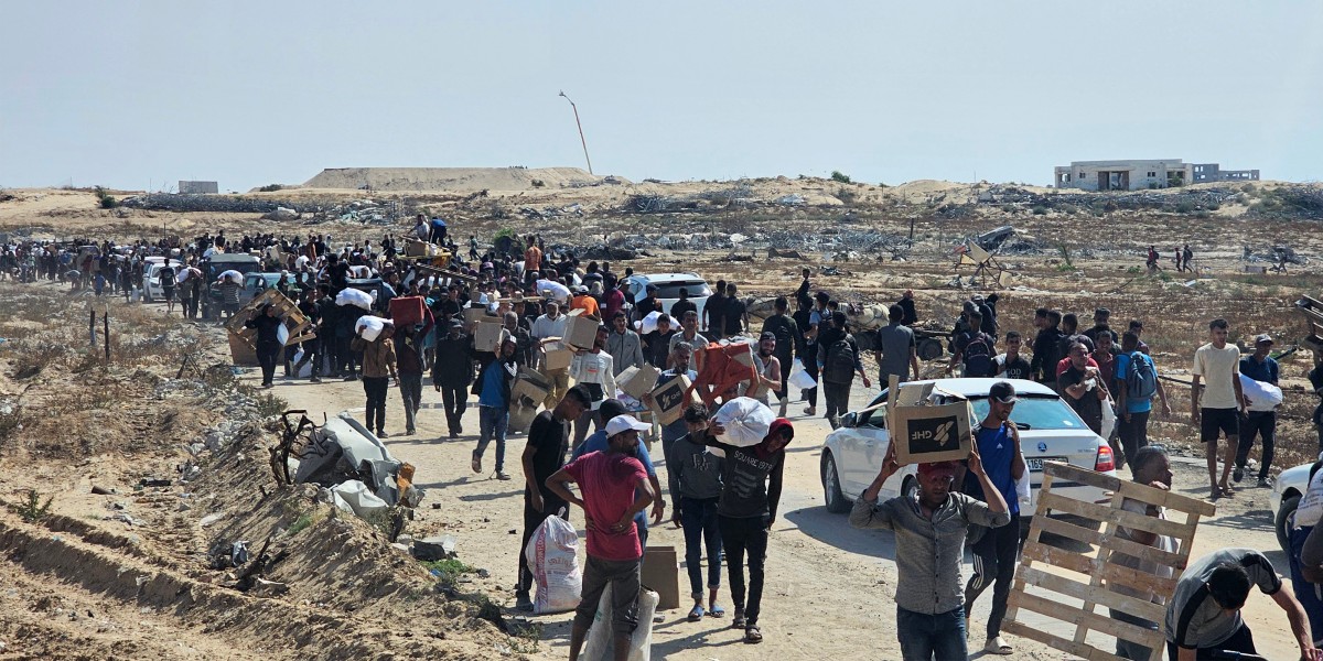 نازحون فلسطينيون يسيرون على طول طريق لتلقي طرود المساعدات الإنسانية من مؤسسة مدعومة من الولايات المتحدة في رفح. (أ ف ب)