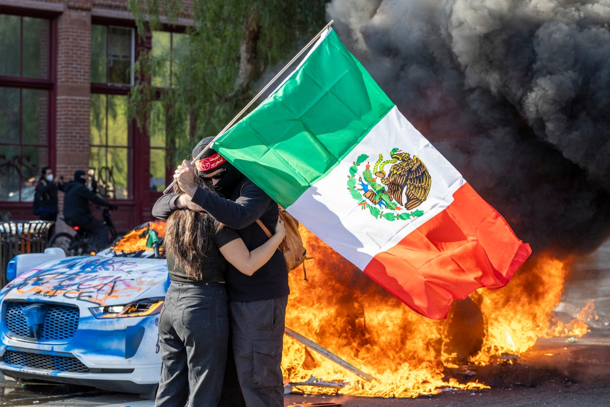  أحرق المتظاهرون في لوس أنجليس سيارات شرطة ورفعوا علم المكسيك. (ا ف ب)