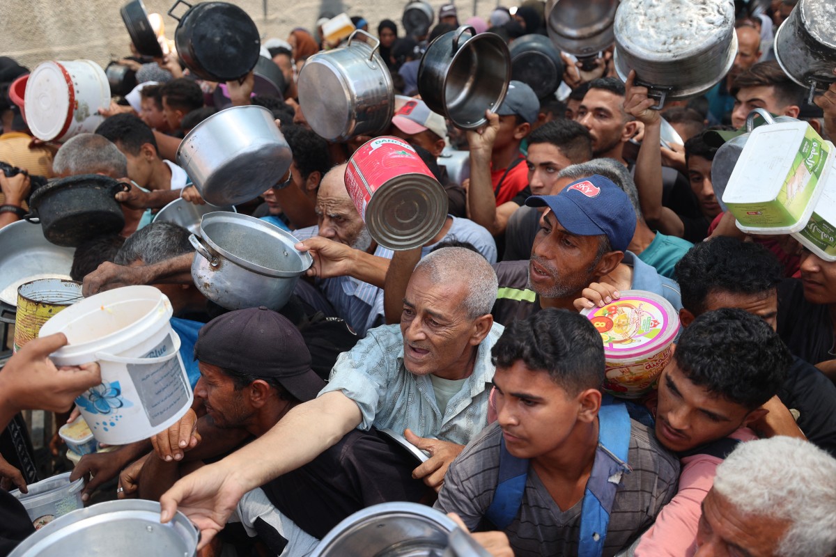 فلسطينيون ينتظرون الحصول على الطعام عند نقطة توزيع في النصيرات، في وسط قطاع غزة (أ ف ب)