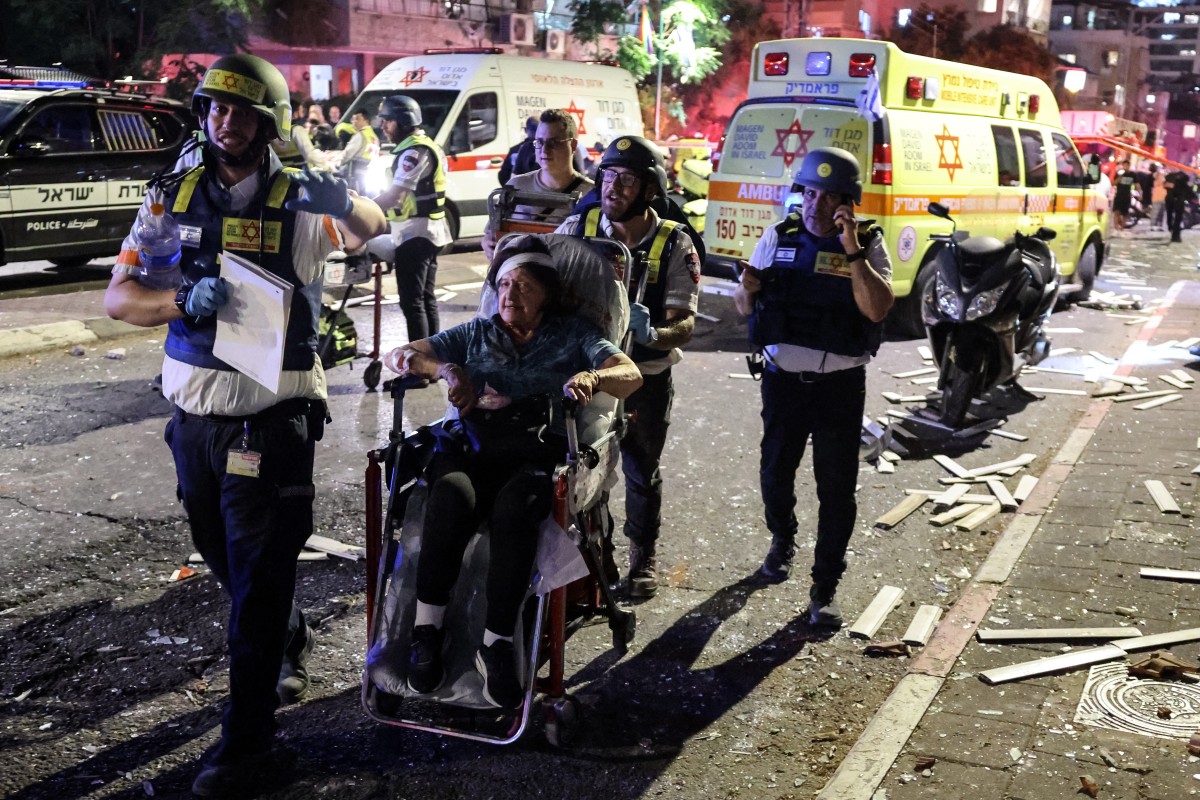 امرأة مصابة يتم إجلاؤها على كرسي متحرك في منطقة أصابها صاروخ أطلق من إيران، في رمات غان بالقرب من تل أبيب (أ ف ب).