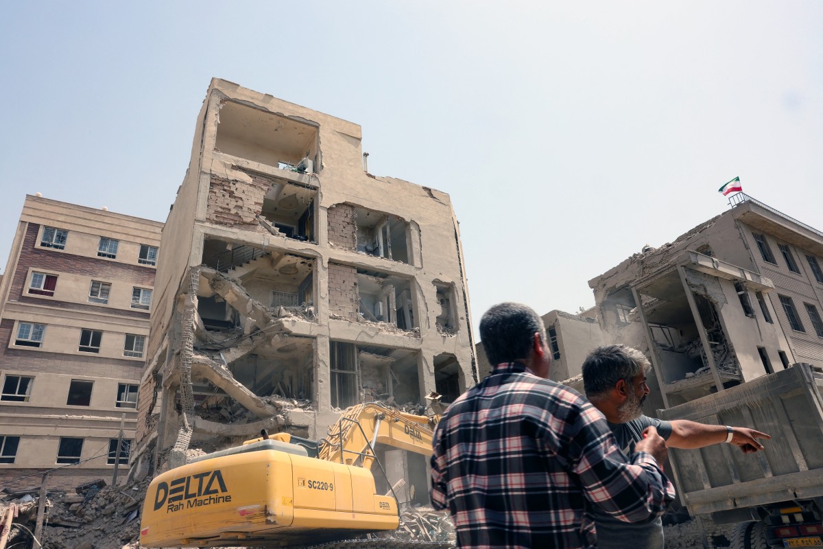 حفارة تُستخدم لإزالة الأنقاض من أمام مبنى استهدفته الغارات الإسرائيلية مؤخرًا في طهران. (أ ف ب)