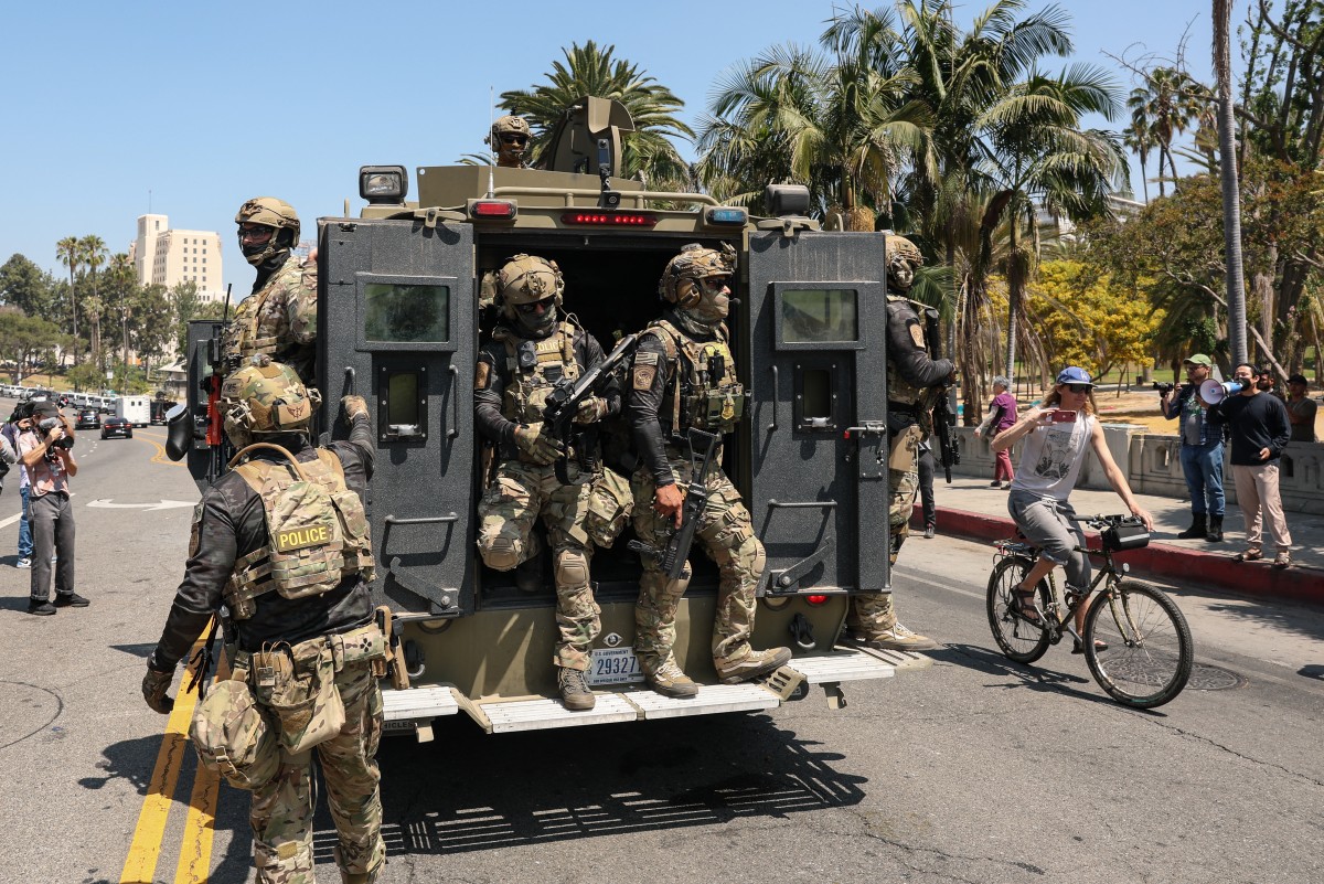 عملاء فيدراليون من الجمارك ودورية الحدود الأميركية (CBP) وهم يستقلون مركبة مدرعة تسير ببطء على شارع ويلشاير، بالقرب من حديقة ماك آرثر في لوس أنجليس، كاليفورنيا (أ ف ب).