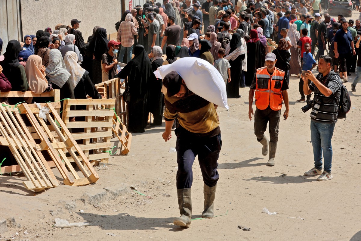 نازح يحمل كيساً من المساعدات الإنسانية في غزة (أ ف ب).