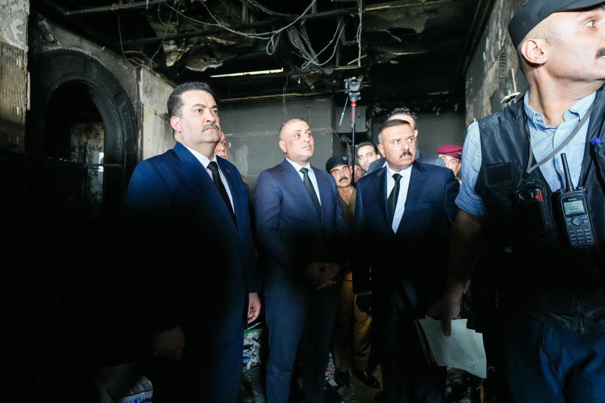 رئيس الوزراء محمد شياع السوداني (يسار) وهو يتفقد الأضرار خلال زيارة إلى مركز تسوق الكورنيش في مدينة الكوت  (أ ف ب)