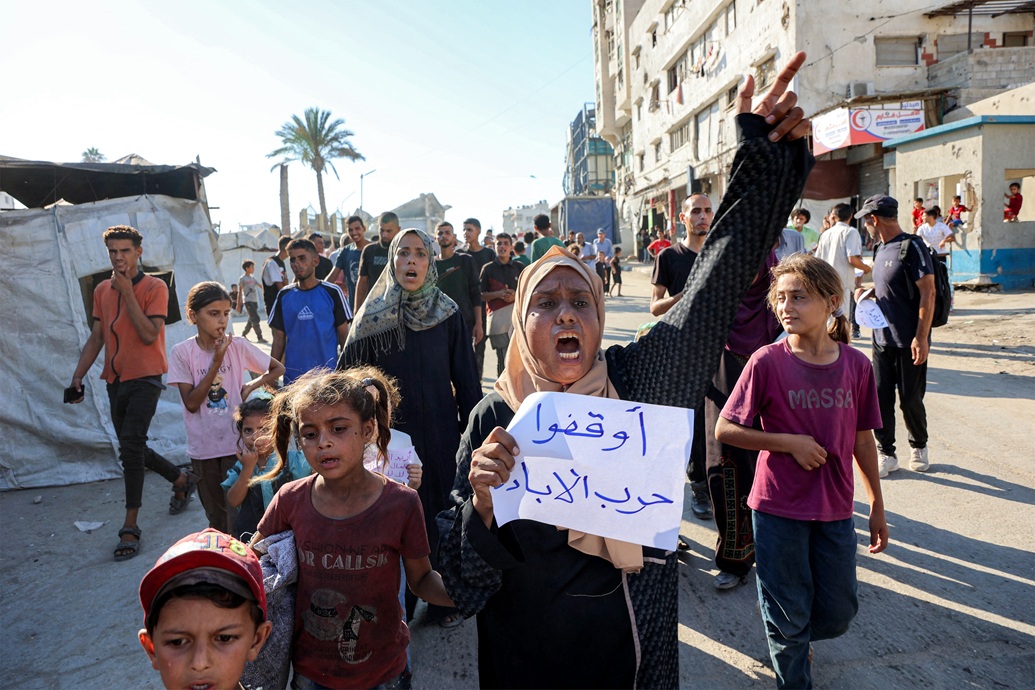 متظاهرون وصحافيون يسيرون في مسيرة احتجاجية ضد الجوع في حي الرمال بمدينة غزة (أ ف ب)