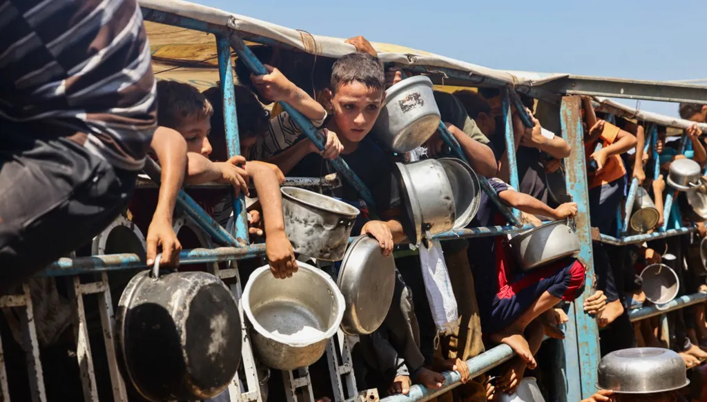 أطفال فلسطينيون ينتظرون وجبة طعام في مطبخ خيري في منطقة المواصي في خان يونس (أ ف ب)