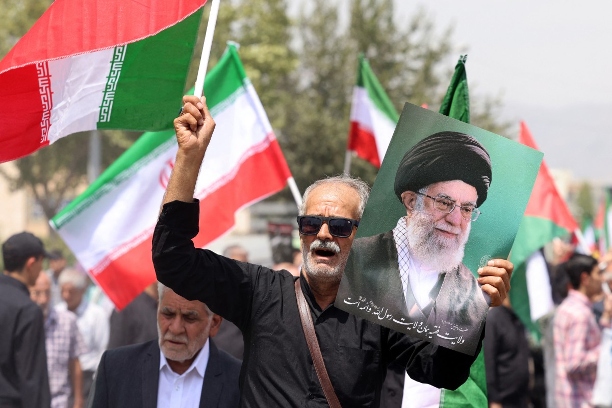 إيراني يرفع صورة خامنئي خلال تظاهرة داعمة لغزة في طهران. (أ ف ب)