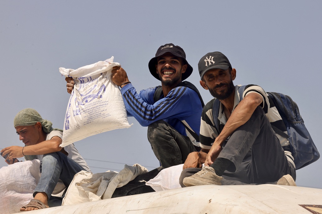 رجل فلسطيني يحمل حقيبة من المساعدات الإنسانية التي حصل عليها في ممر رفح (أ ف ب)