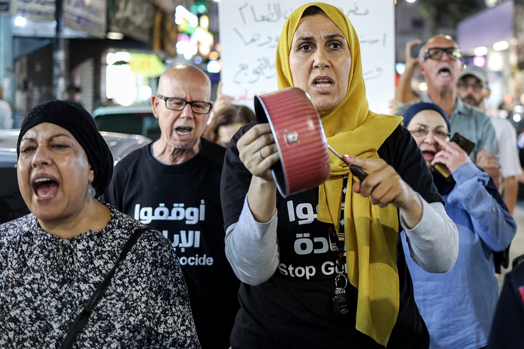 امرأة تقرع على قدر طبخ أثناء مسيرة تضامنية مع الفلسطينيين في مدينة رام الله (أ ف ب)