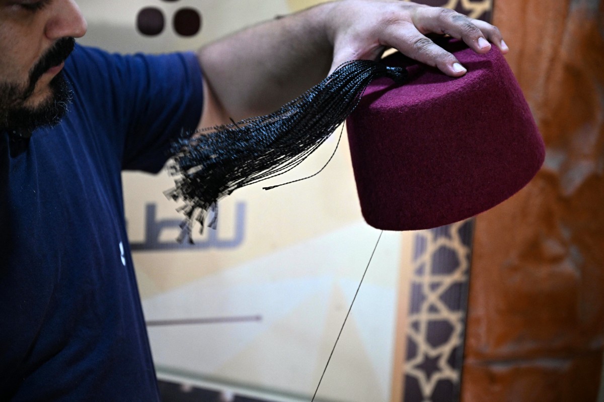 الحرفي اللبناني محمد الشعار يخيط شرابة على طربوش (أ ف ب).