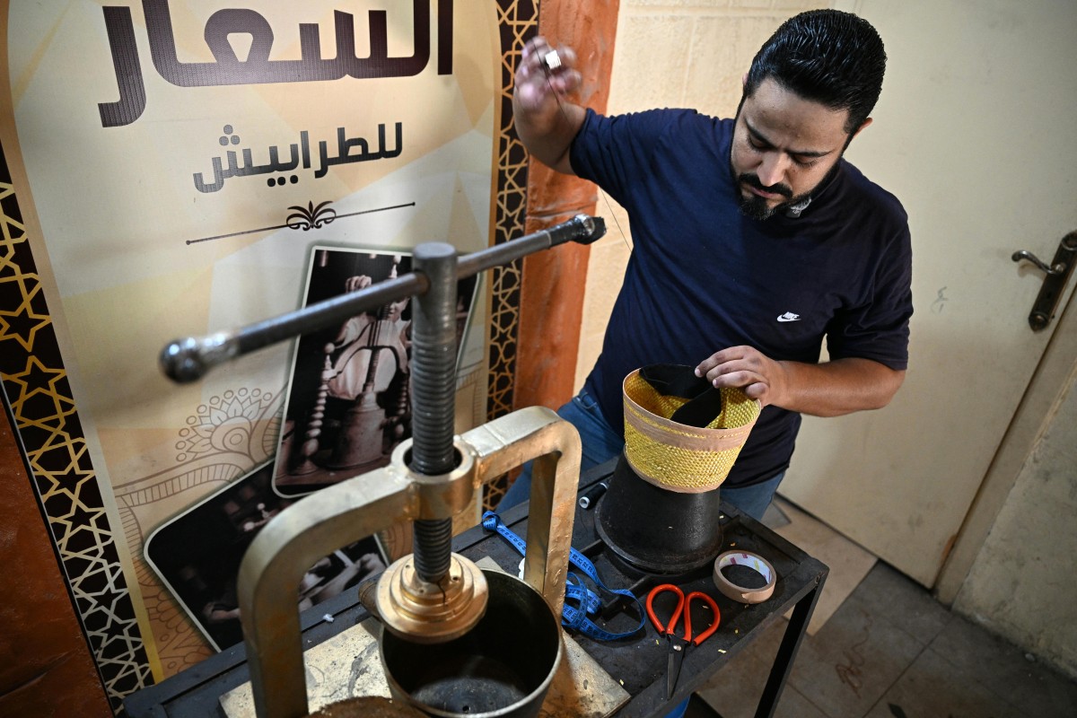 الحرفي اللبناني محمد الشعار يخيط حافة طربوش (أ ف ب).